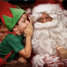 young child whispering into Santa's ear