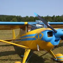 Yellow and blue single-engine airplane on a grassy field.
