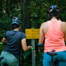 Two bikers looking at the sign for Kunjamuk Cave.