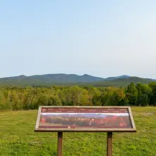 An interpretive sign at a roadside stop overlooking several mountains