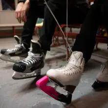 A couple people lacing up their ice skates