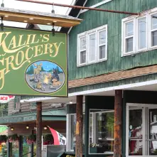 A green sign with gold lettering reading 'Kalil's Grocery"