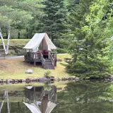 A fabric tent covering a raised deck next to the pond