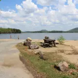 A beach with a boat ramp, picnic table, and mountain views