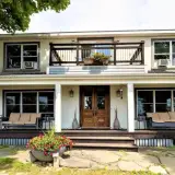 Exterior of The Chateau with grand entry onto wrap-around front porch, elevated balcony and comfortable seating options all around