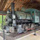 An antique steam engine under a wooden structure