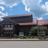 An entryway to the museum with stairs, a large sign with the name and a massive wooden chair by the sidewalk
