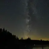 The glorious milky way seen through dark skies over the lake and surrounding pines