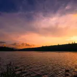 Gorgeous sunset of golden light into violets and deep purples over the gentle waves of a lake