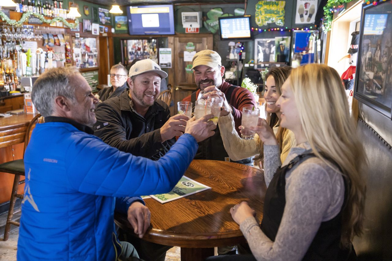 A group of friends cheers drinks at a tavern. 