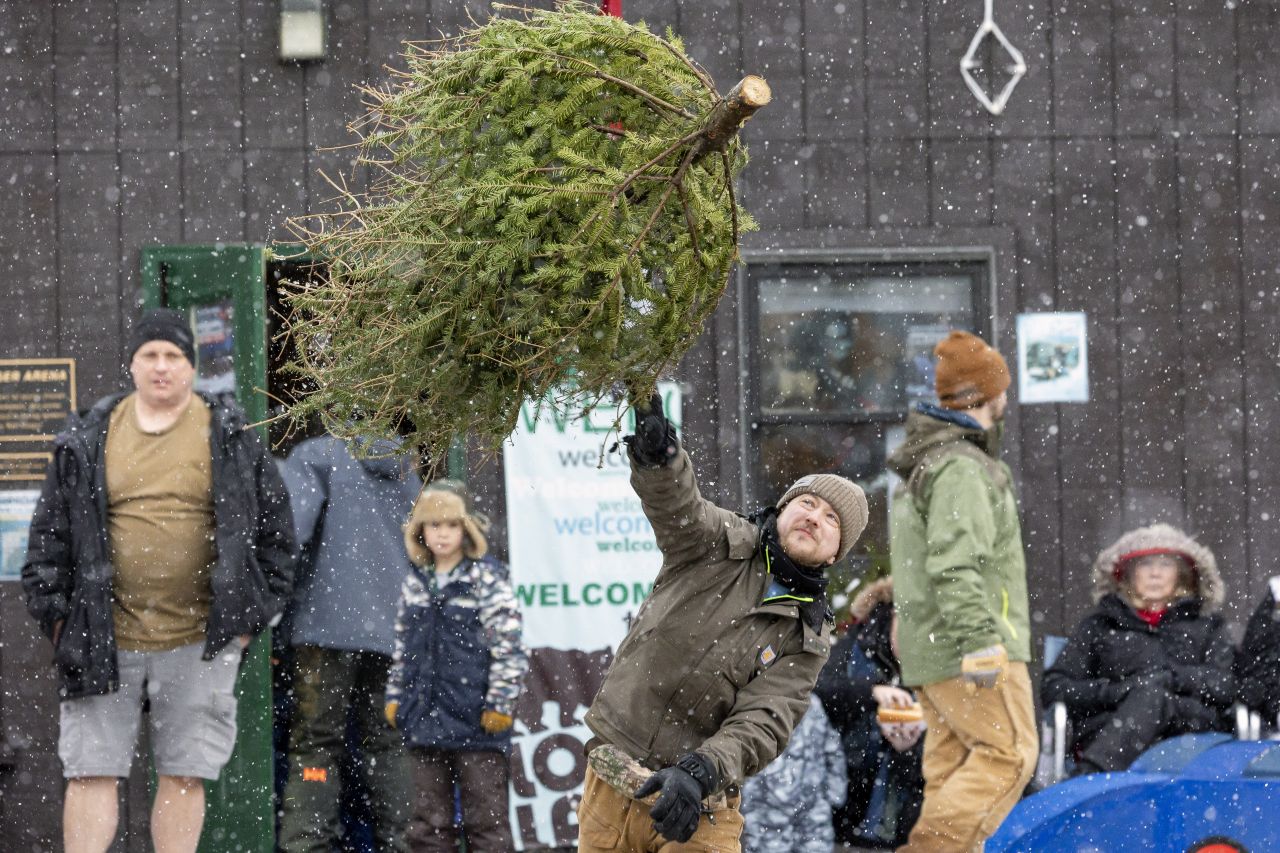 A man laughs while throwing a Christmas tree high into the air during the Christmas Tree Toss contest at the Long Lake Winter Carnival.