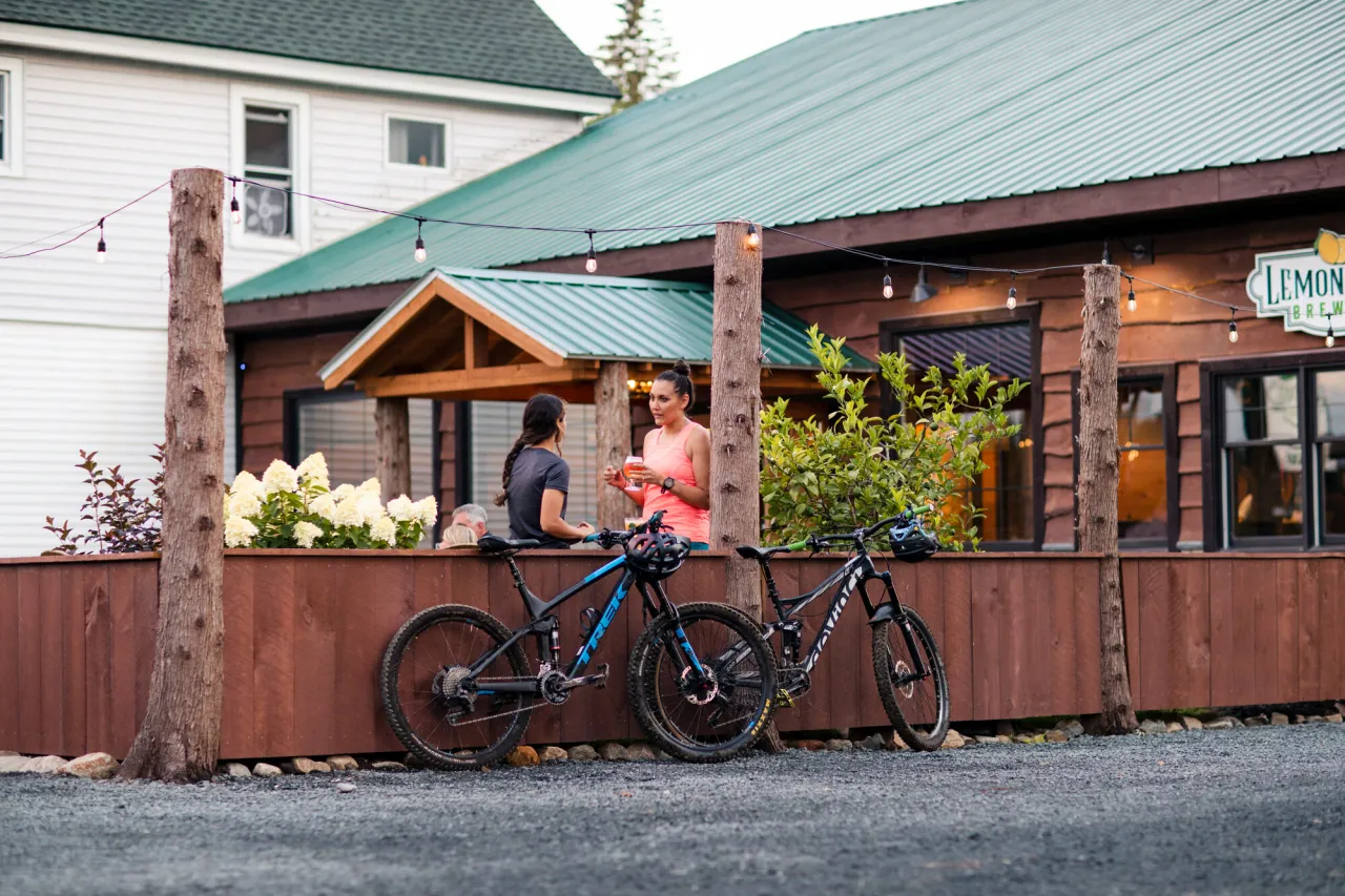 Two women enjoy beers on a brewery patio.