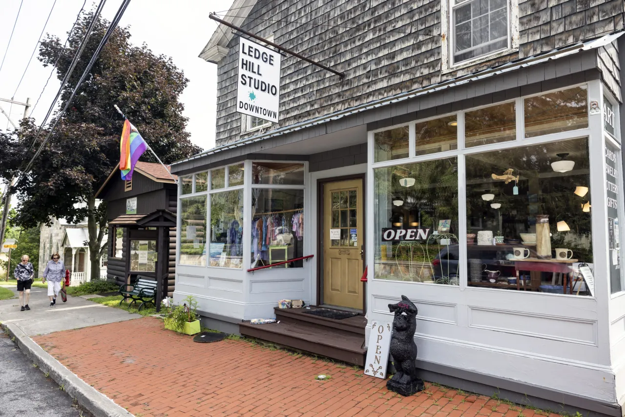 The outside of a cape cod style storefront, filled with gift shop items and an art gallery.