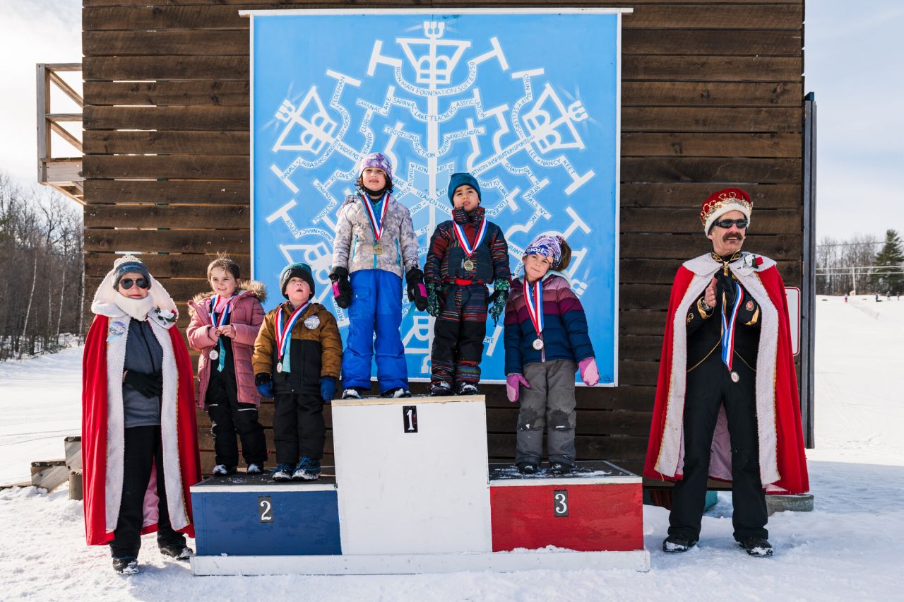 A group of kids stand for medals at a winter carnival. 
