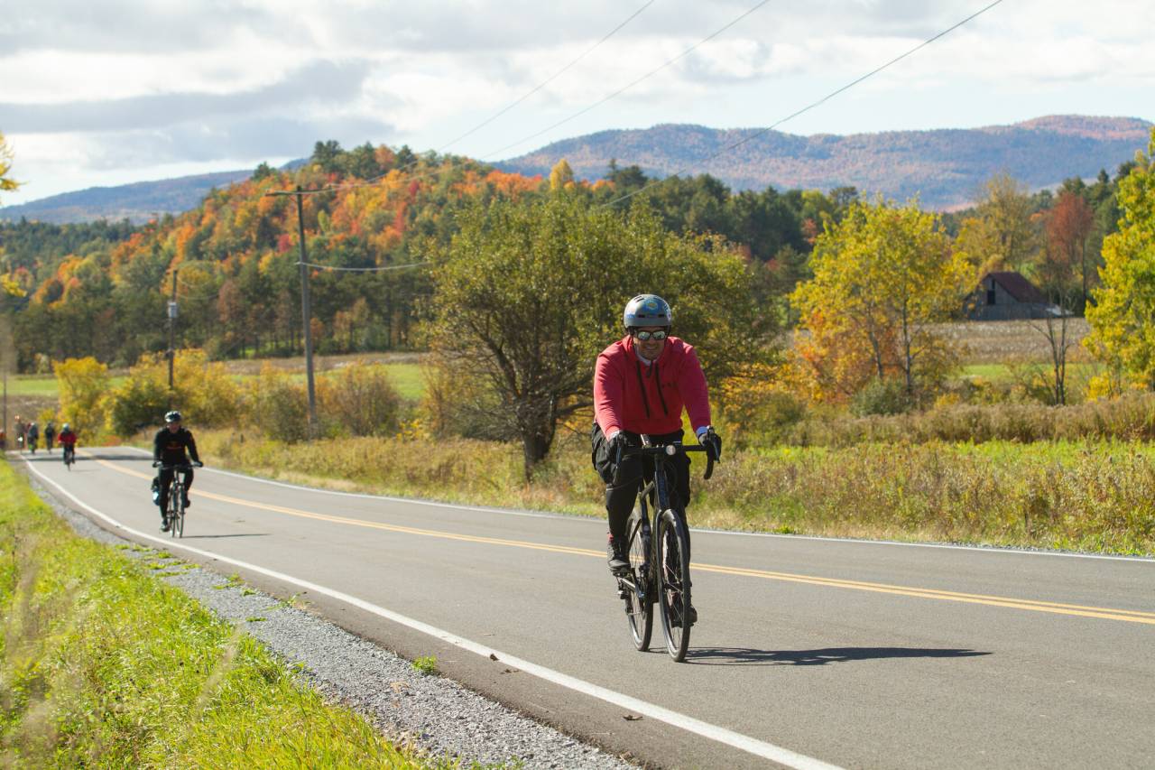 A man rides his bike up a hill in fall. 