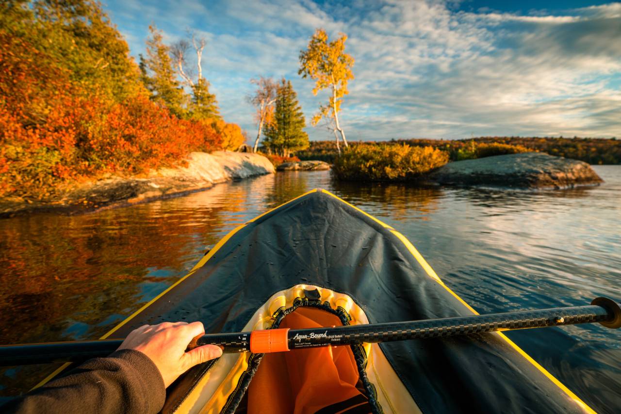 A person paddling on Blue Mountain Lake in the fall.