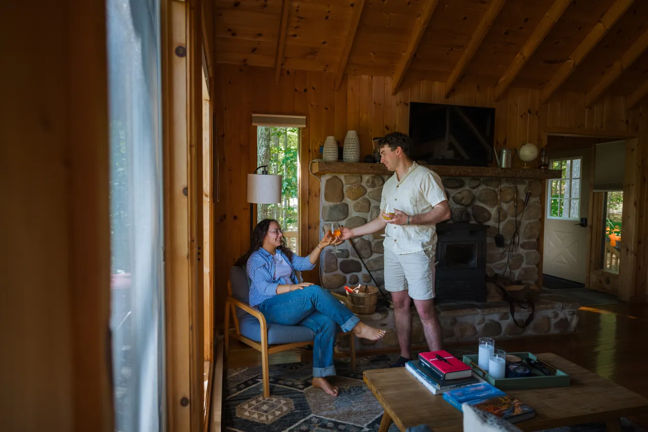 Man hands woman sitting in chair by window a glass of wine in an elegant cabin