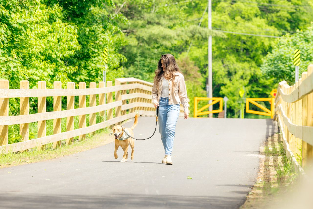 A woman walking her dog on the Adirondack Rail Trail.