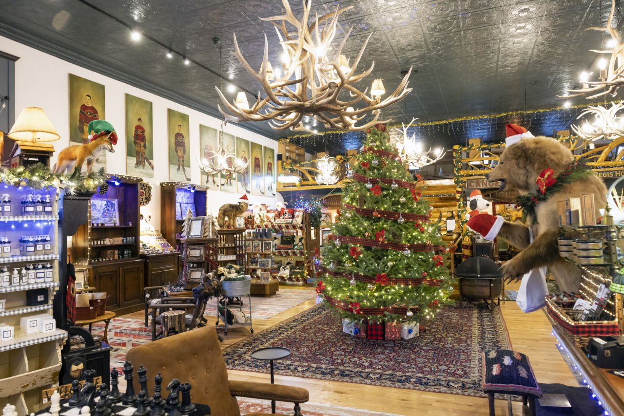 The interior of a high-end Adirondack gift shop, featuring an antler chandelier, gifts on display, and a taxidermied bear.