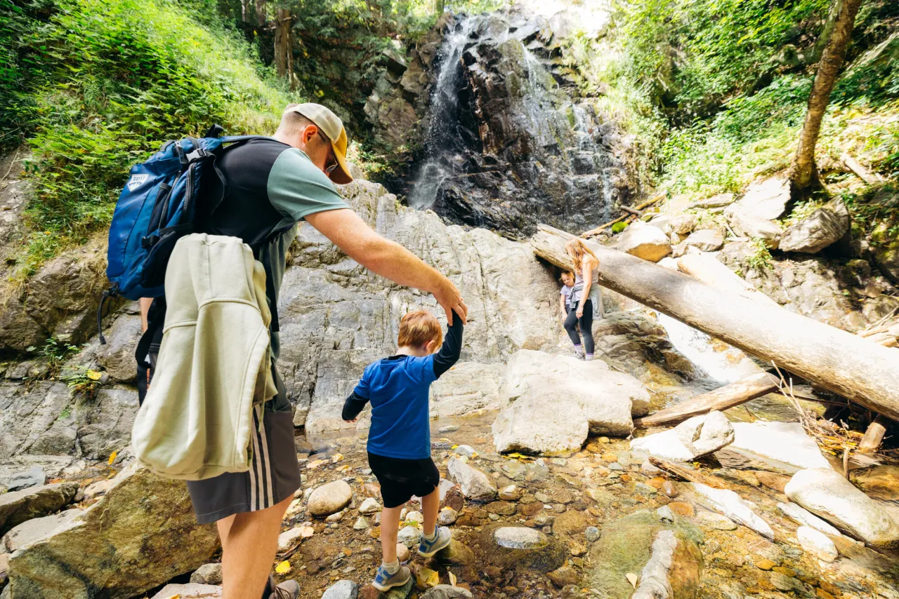 A family explores a waterfall in summer.