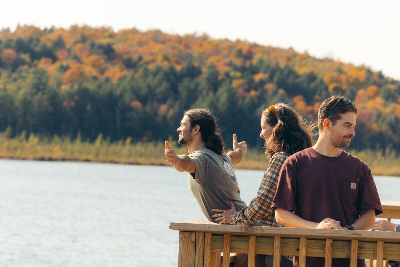 A group of friends laugh and talk on a pier on a lake.