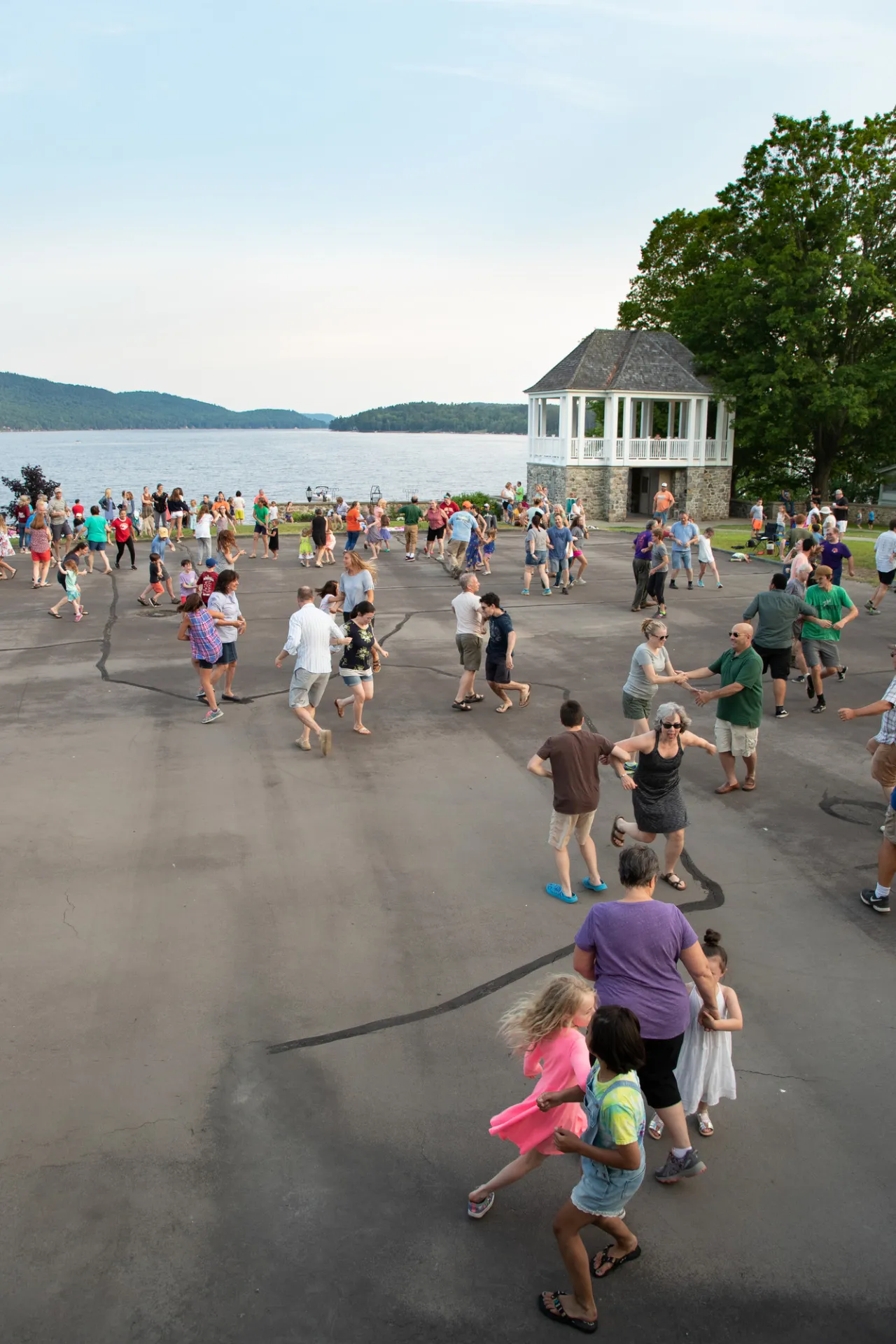 A group of people dance at a park along a lake.