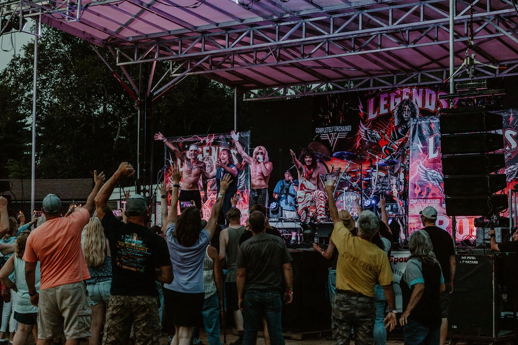 A crowd of people cheer at an outdoor rock concert. 