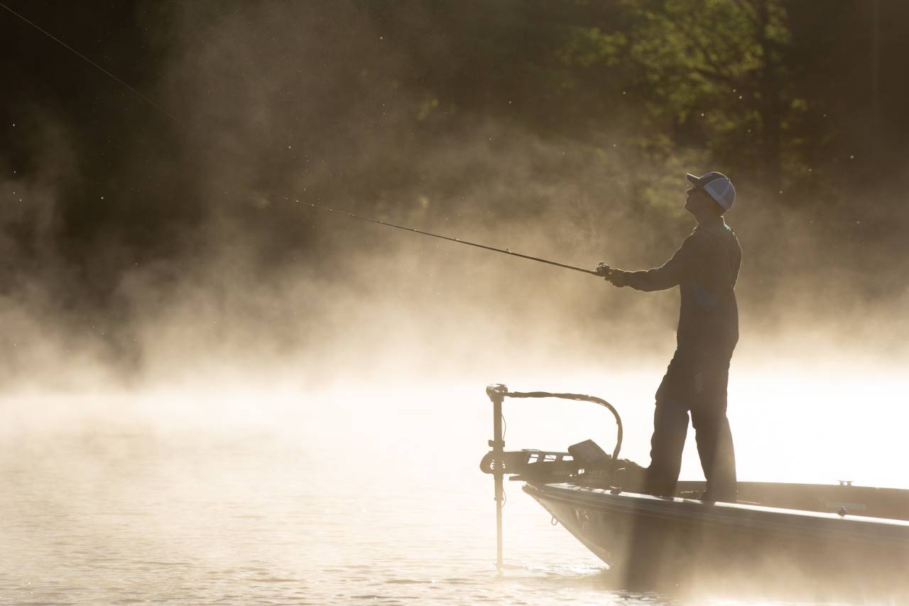 A misty morning with people fishing from a boat