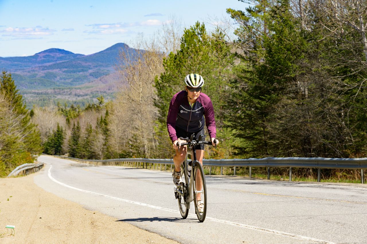 A woman cycles up a hill in spring. 