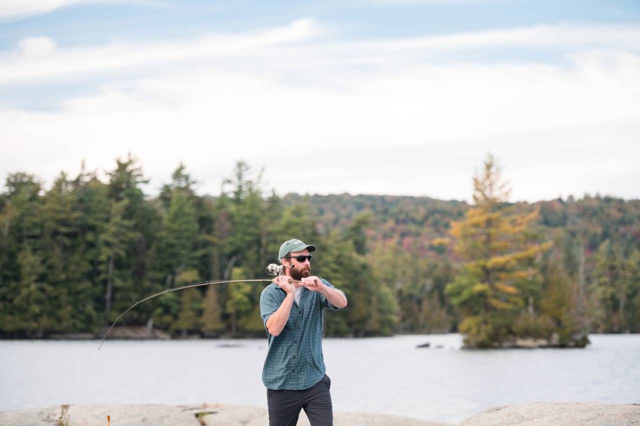 A man casts off on a lake. 