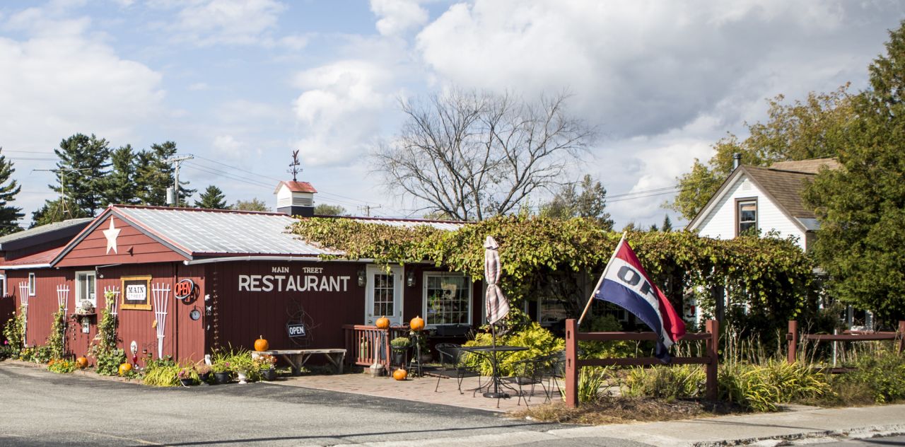 A red restaurant surrounded by shrubbery and an open flag.