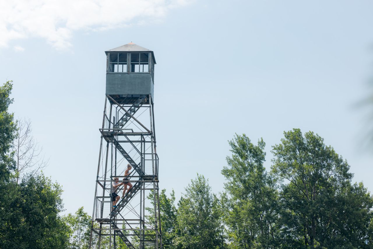 A firetower stands above the trees in summer. 
