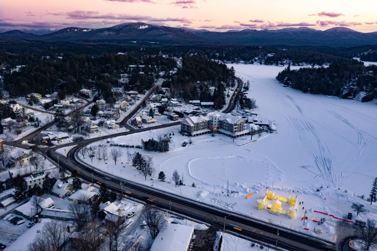 A lake and hotel blanketed in snow in the mountains.