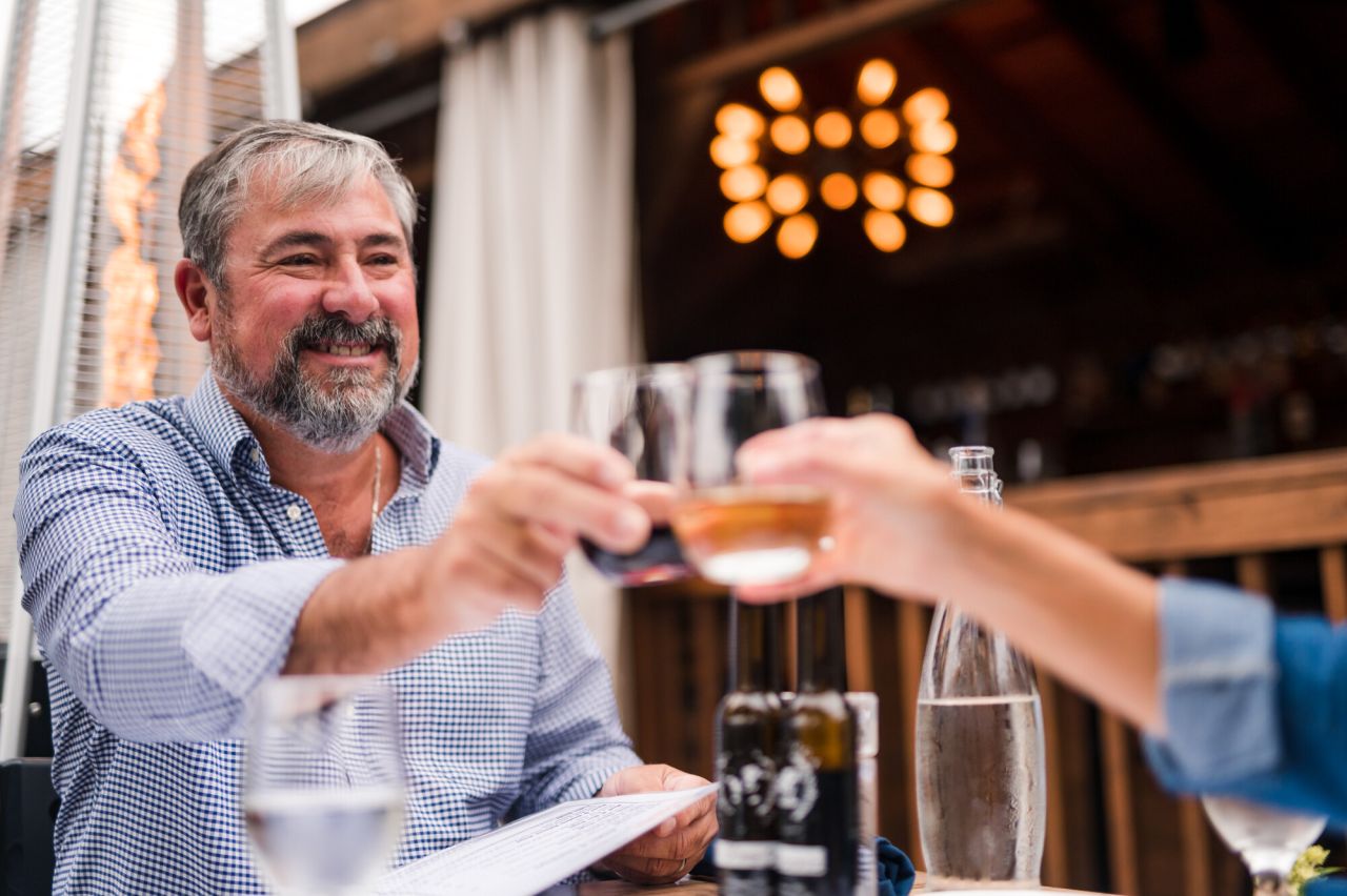 A man and woman cheers glasses at an outdoor restaurant.