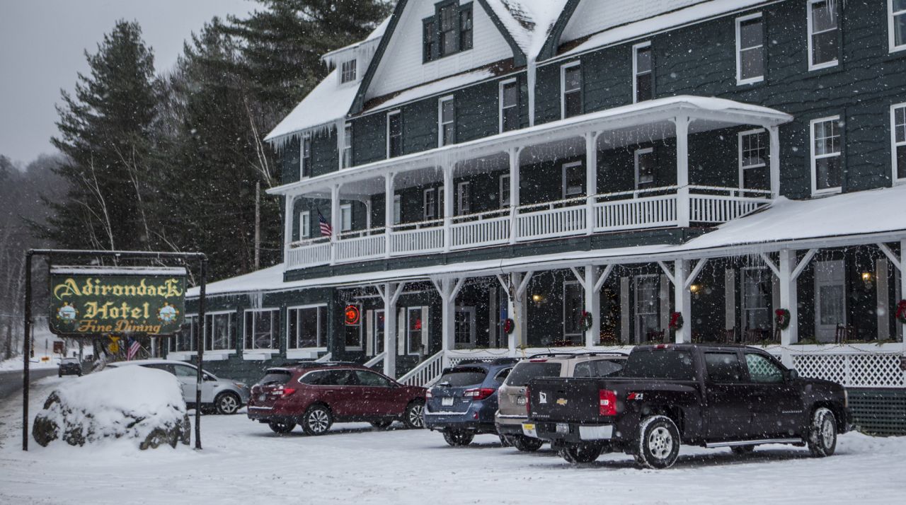 A green vintage hotel in the snow with a long wrap around porch.