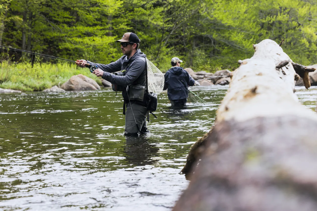 two men fly fish in a river. 