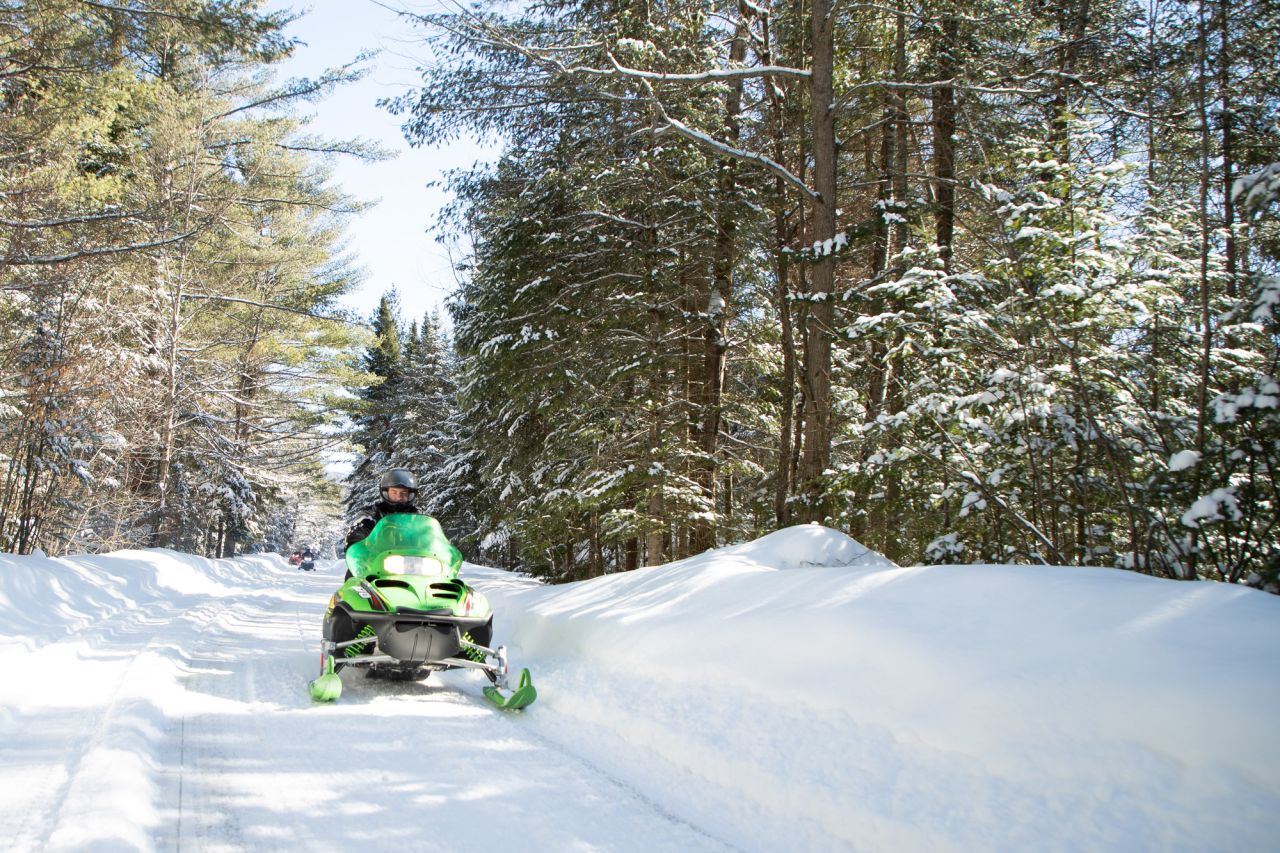 A man rides a snowmobile on a snowy trail.