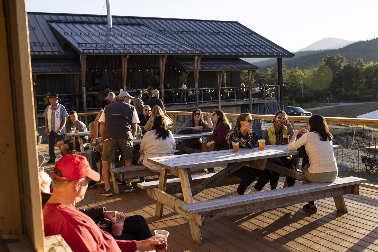 An outdoor patio of a restaurant filled with people at sunset. 