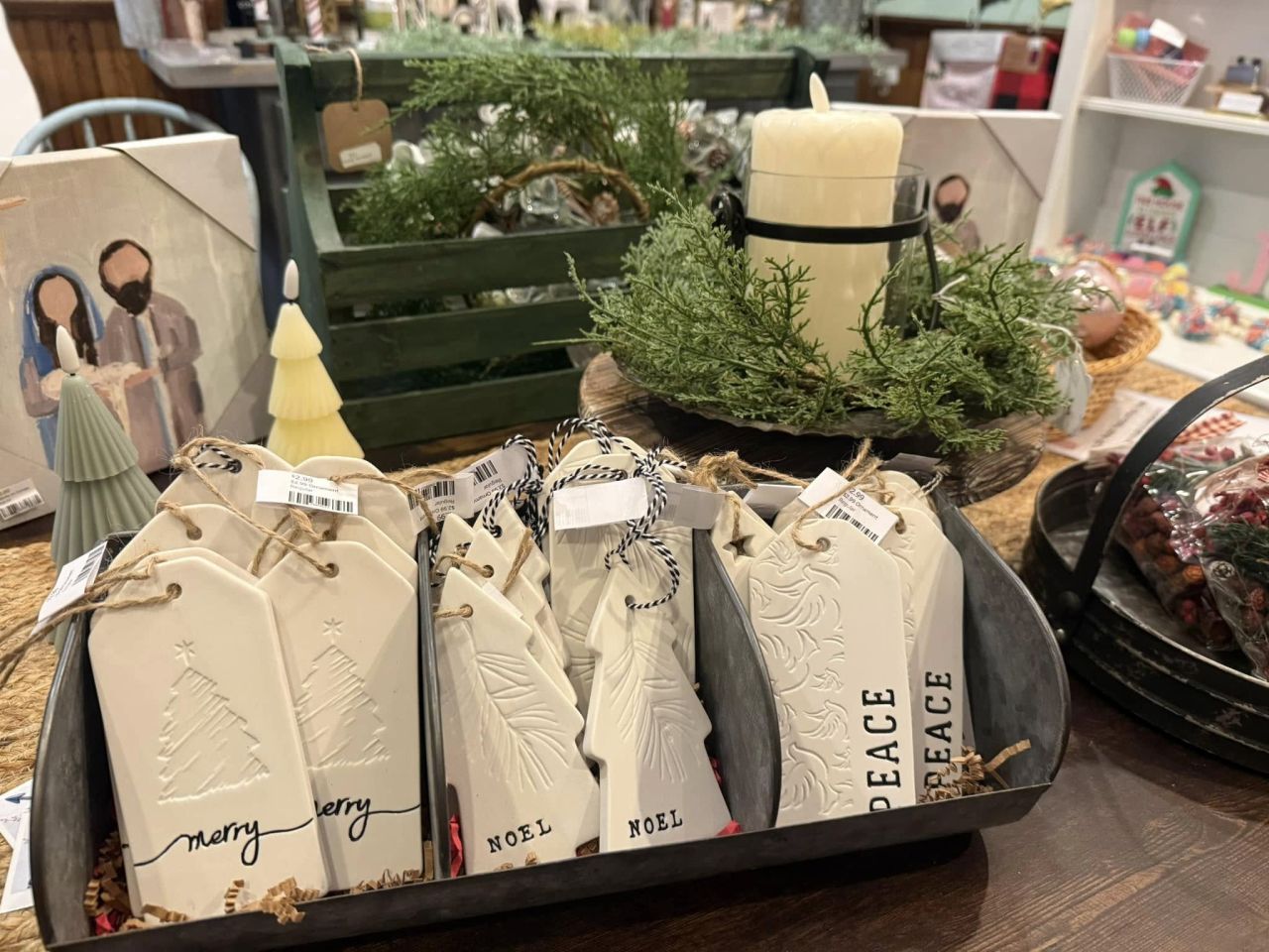 Close-up of a Christmas display on a store table: porcelain Christmas ornaments with a fir-trimmed candle.