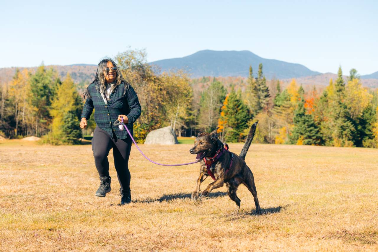 A man runs with his dog in fall. 