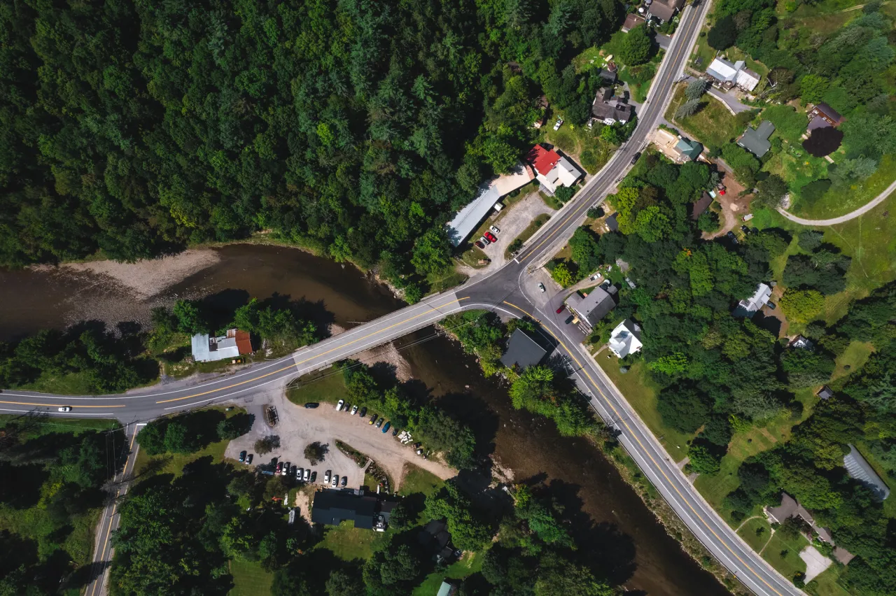 Aerial summertime image of Upper Jay T intersection with Upper Jay Art Center visible and river cutting through the frame