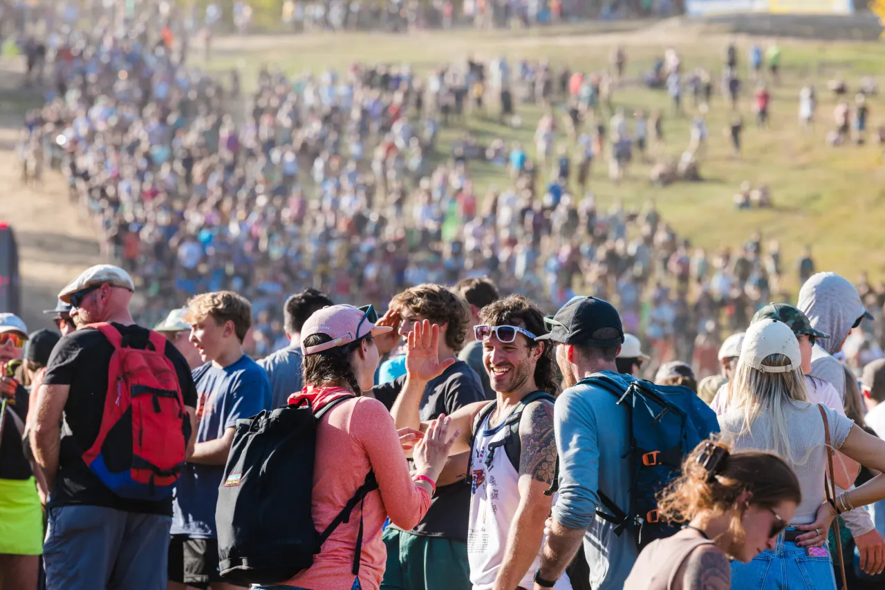 Large crowd spread out over ski slope in summer at UCI MTB World Cup at Whiteface Mountain. Men in foreground high five