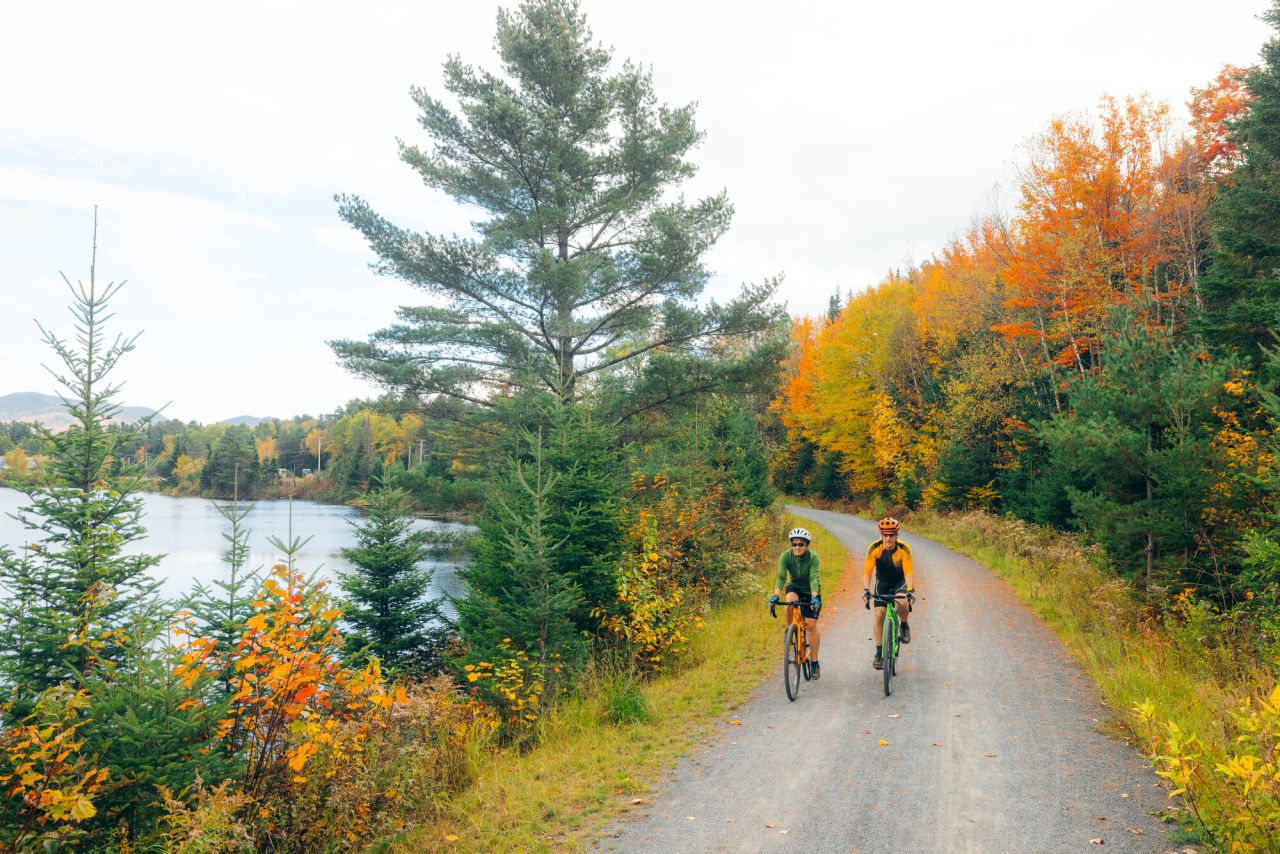 Two people ride bikes on a fall trail.