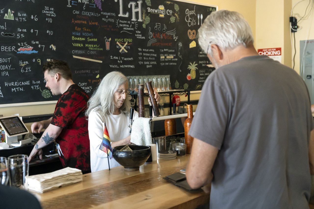 A woman pours beer behind an eclectic bar.
