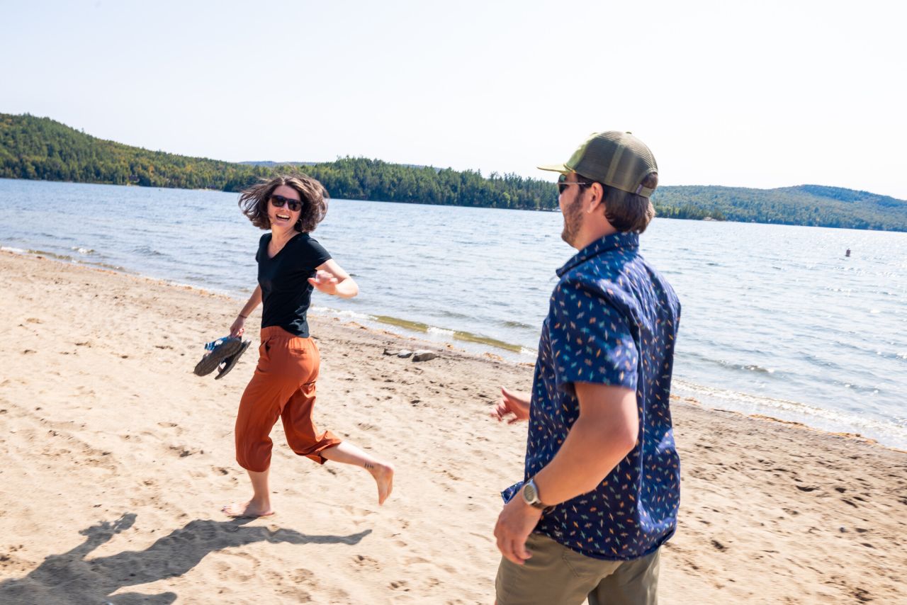 A man and woman jog on a beach. 