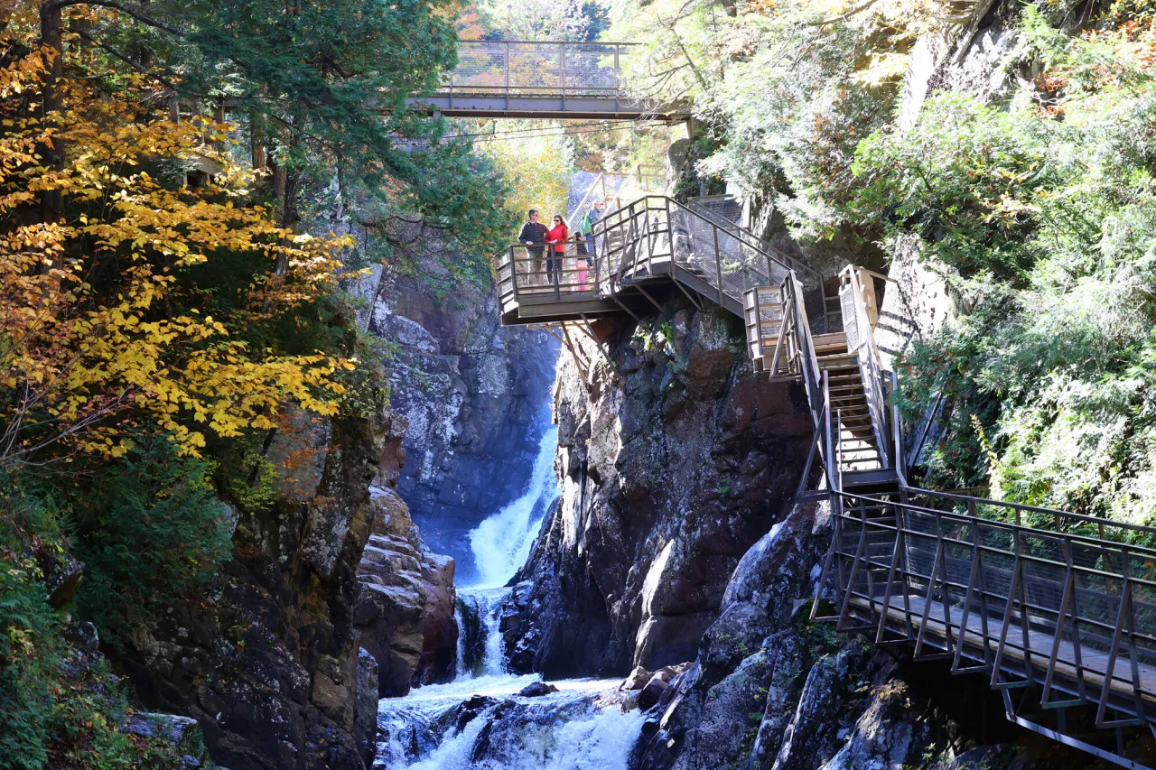 A man and woman stand at the top of a set of waterfalls.