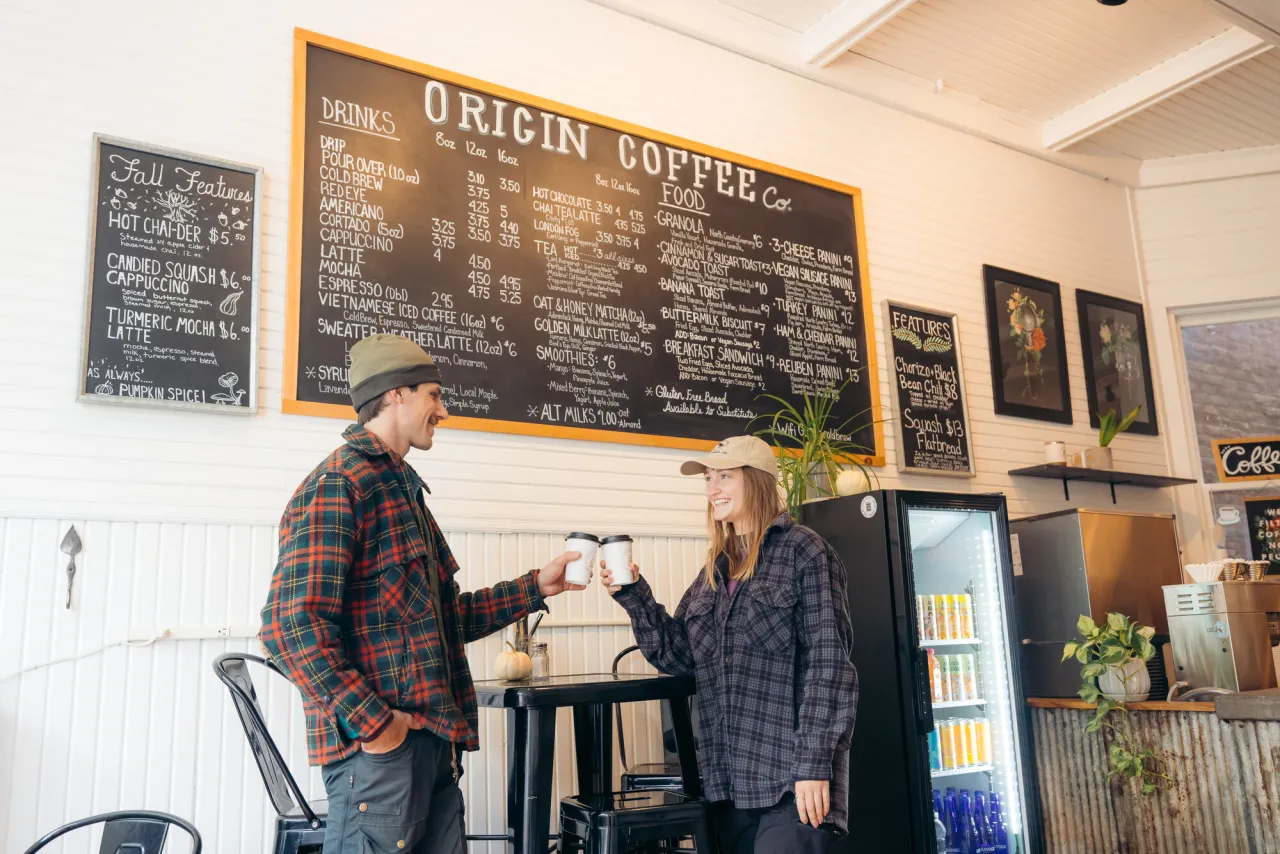 A man and woman enjoy coffee at a brightly lit coffee shop.