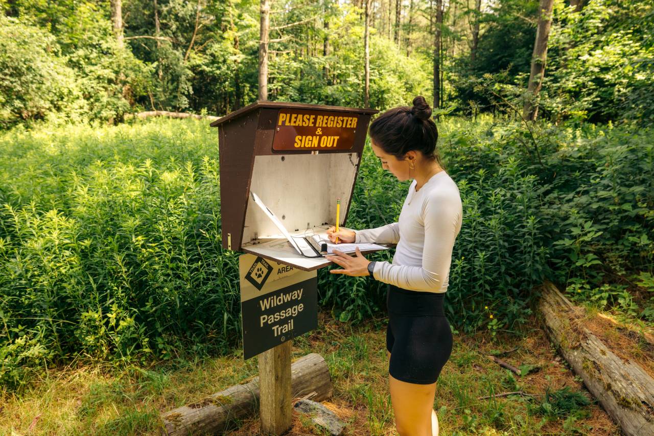 A woman signs in to a trail. 
