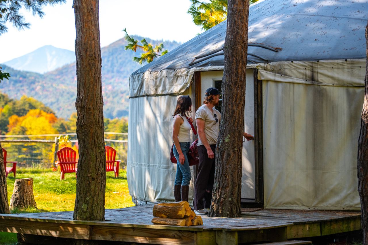 A man and woman walk into a canvas yurt on a farm. 
