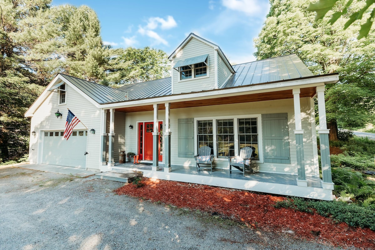 A cottage with barn-themed accents and a covered porch outside. 